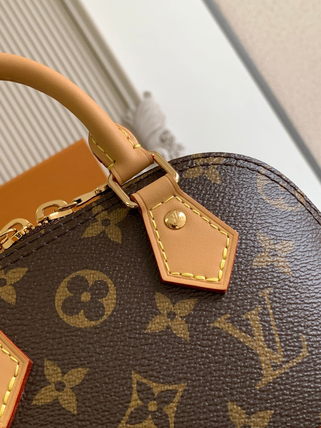 Louis Vuitton monogram bag close-up with tan leather tab and gold button