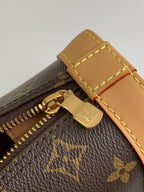 Louis Vuitton monogram bag close-up of zipper pull and tan leather corner patch