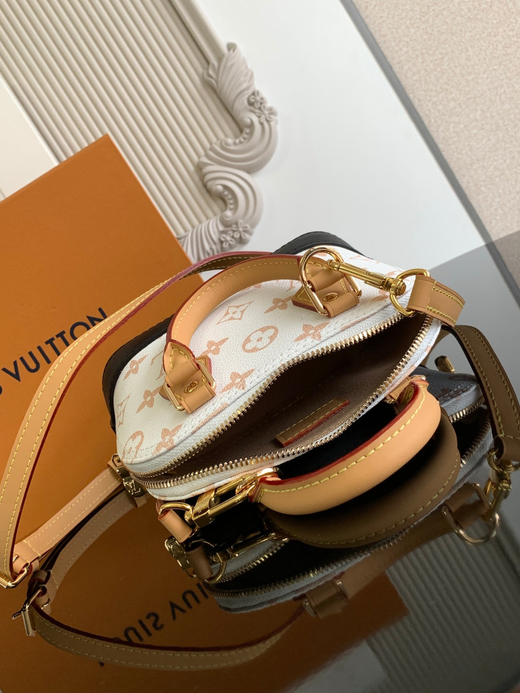 Louis Vuitton small top-handle bag with white monogram canvas, tan straps, and zipper