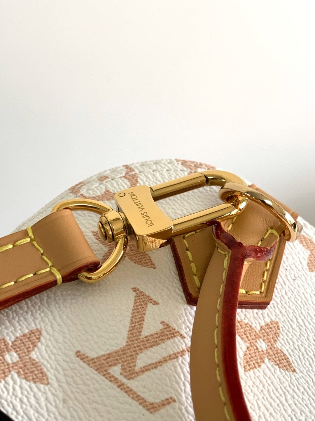 Louis Vuitton bag clasp and D-ring hardware on white monogram canvas with tan strap