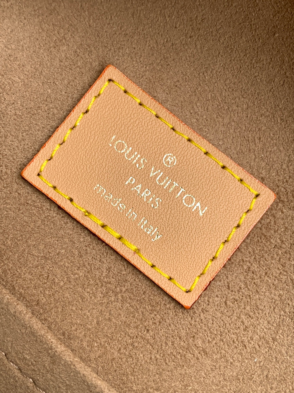 Louis Vuitton bag authenticity label on tan leather patch with yellow stitching