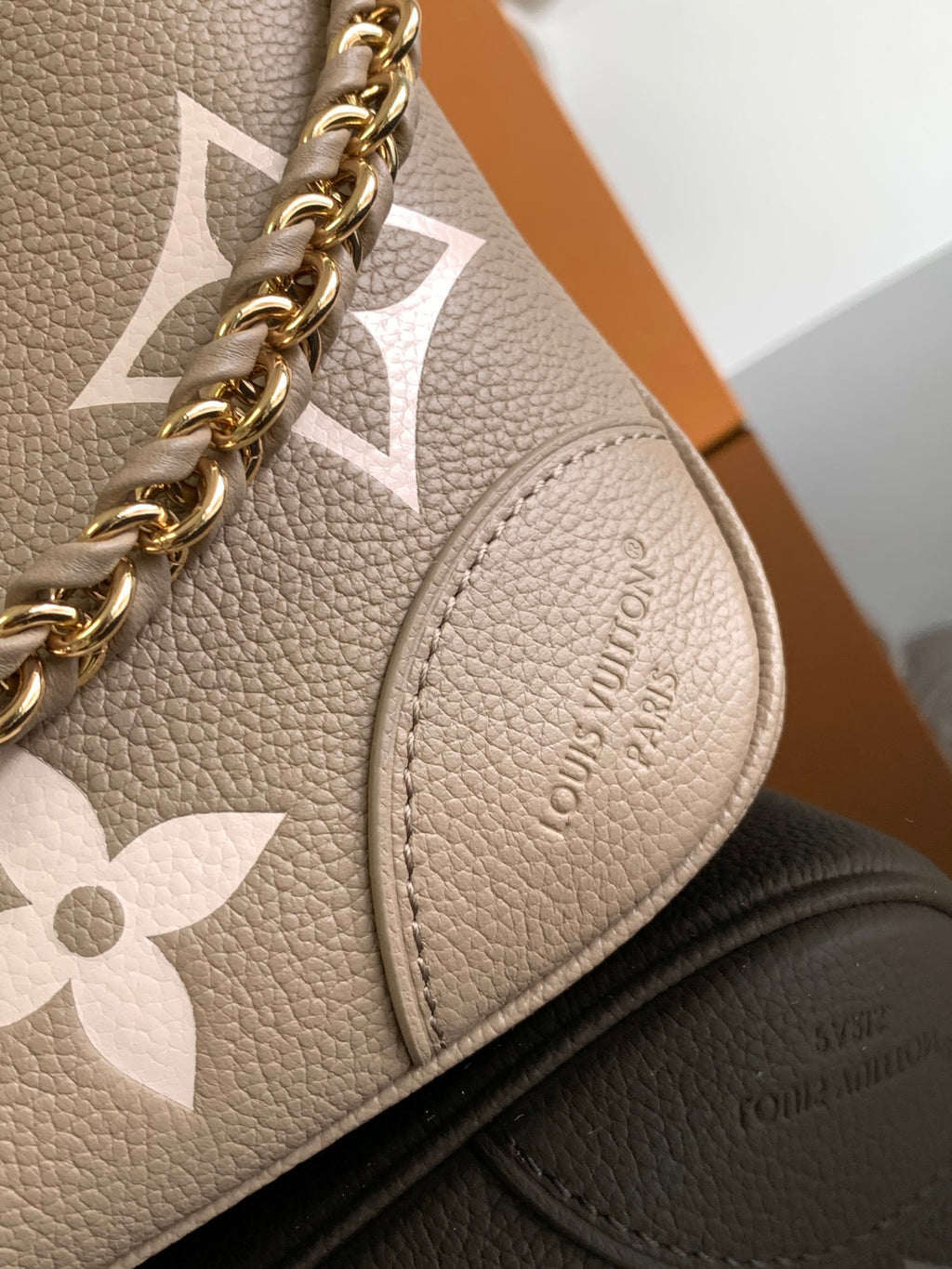 Louis Vuitton monogram bag close-up with gold chain and beige floral pattern