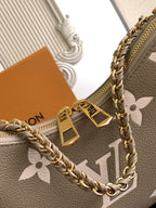 Louis Vuitton monogram bag detail with gold clasp, chain links, and logo charm