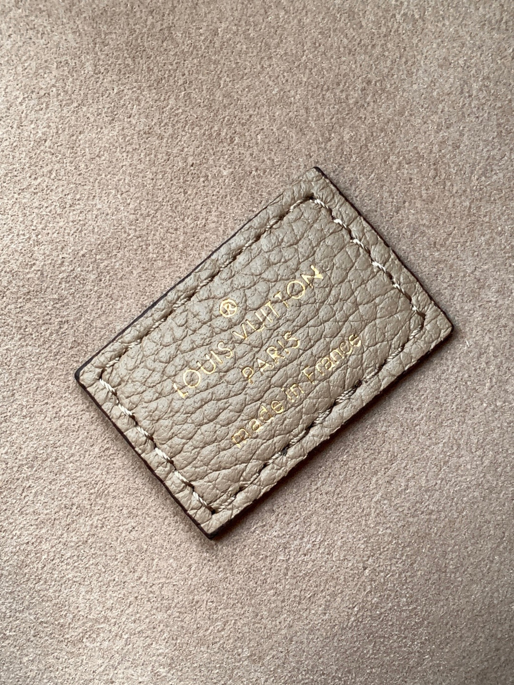 Small monogram leather card holder in light gray with stitched logo on front.