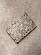 Small monogram leather card holder in light gray with stitched logo on front.