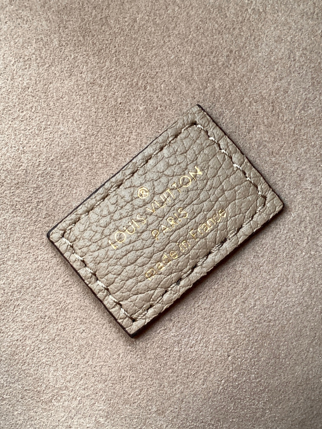 Small monogram leather card holder in light gray with stitched logo on front.