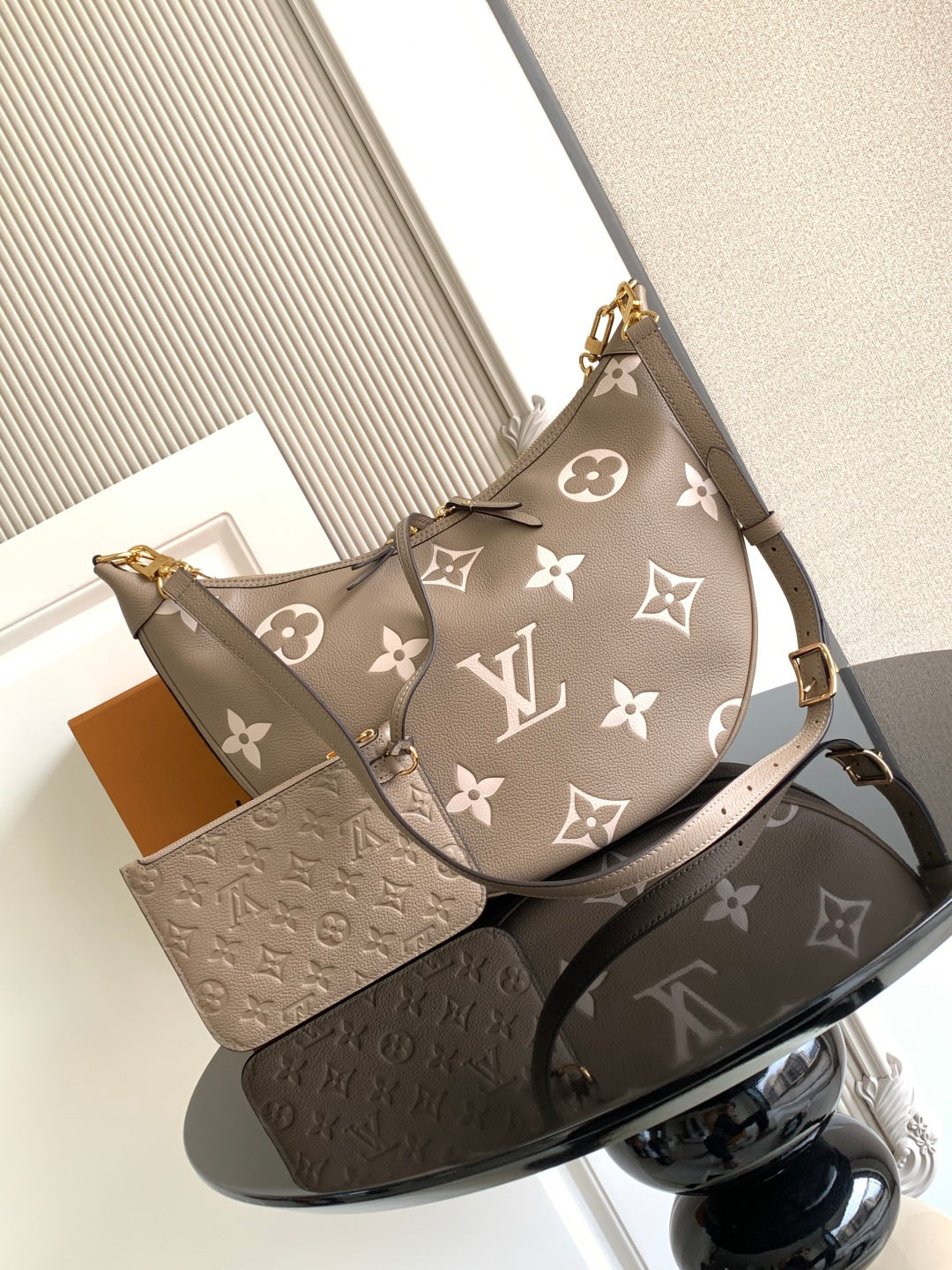 Monogram hobo bag with taupe fabric, white logo motifs, and gold shoulder strap hardware.