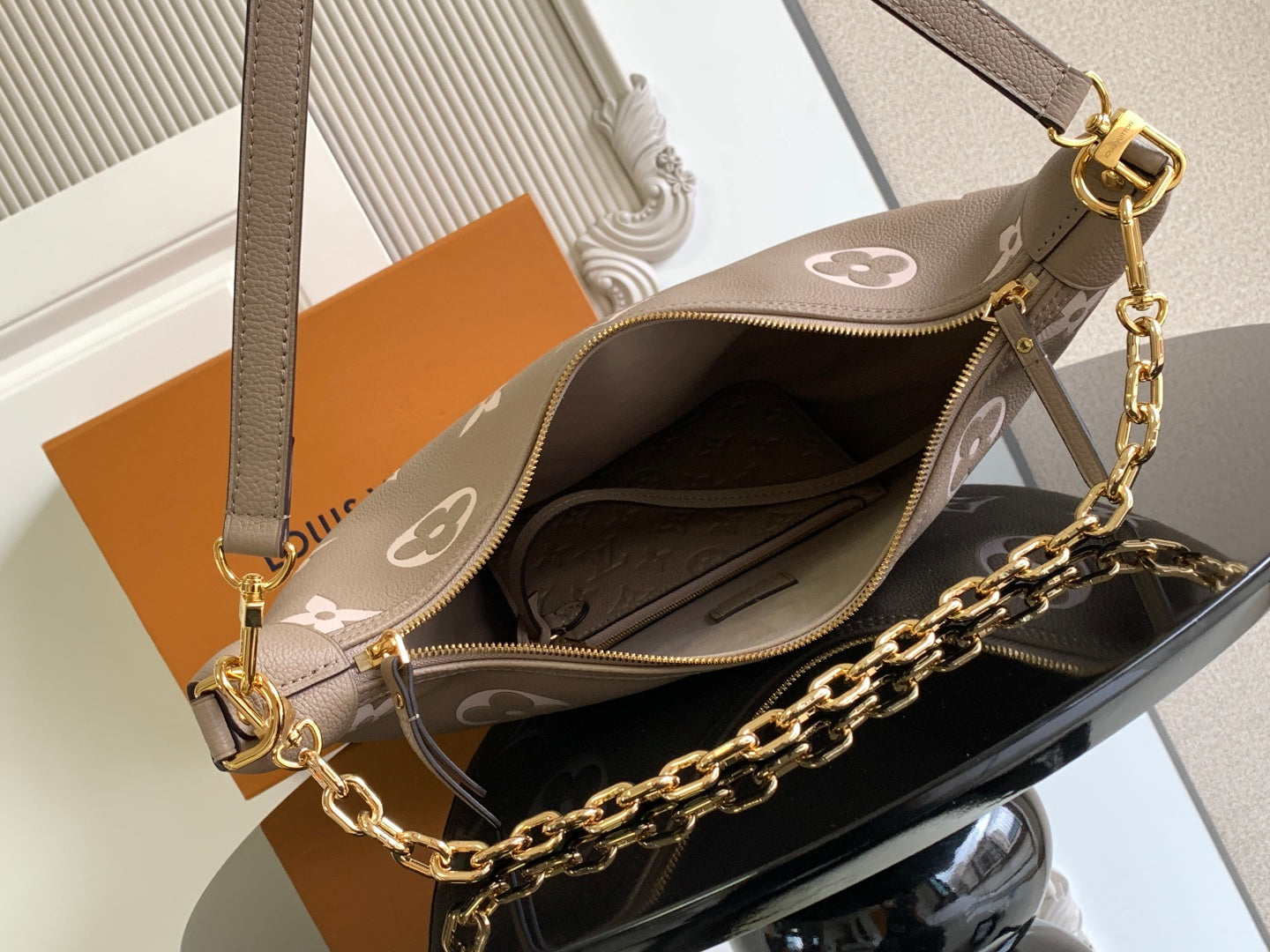 Open monogram bag in taupe with white pattern, zip top, and gold chain strap.