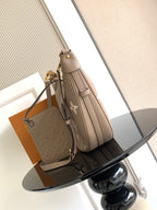 Monogram shoulder bag with taupe leather, gold hardware, and detachable strap charm.