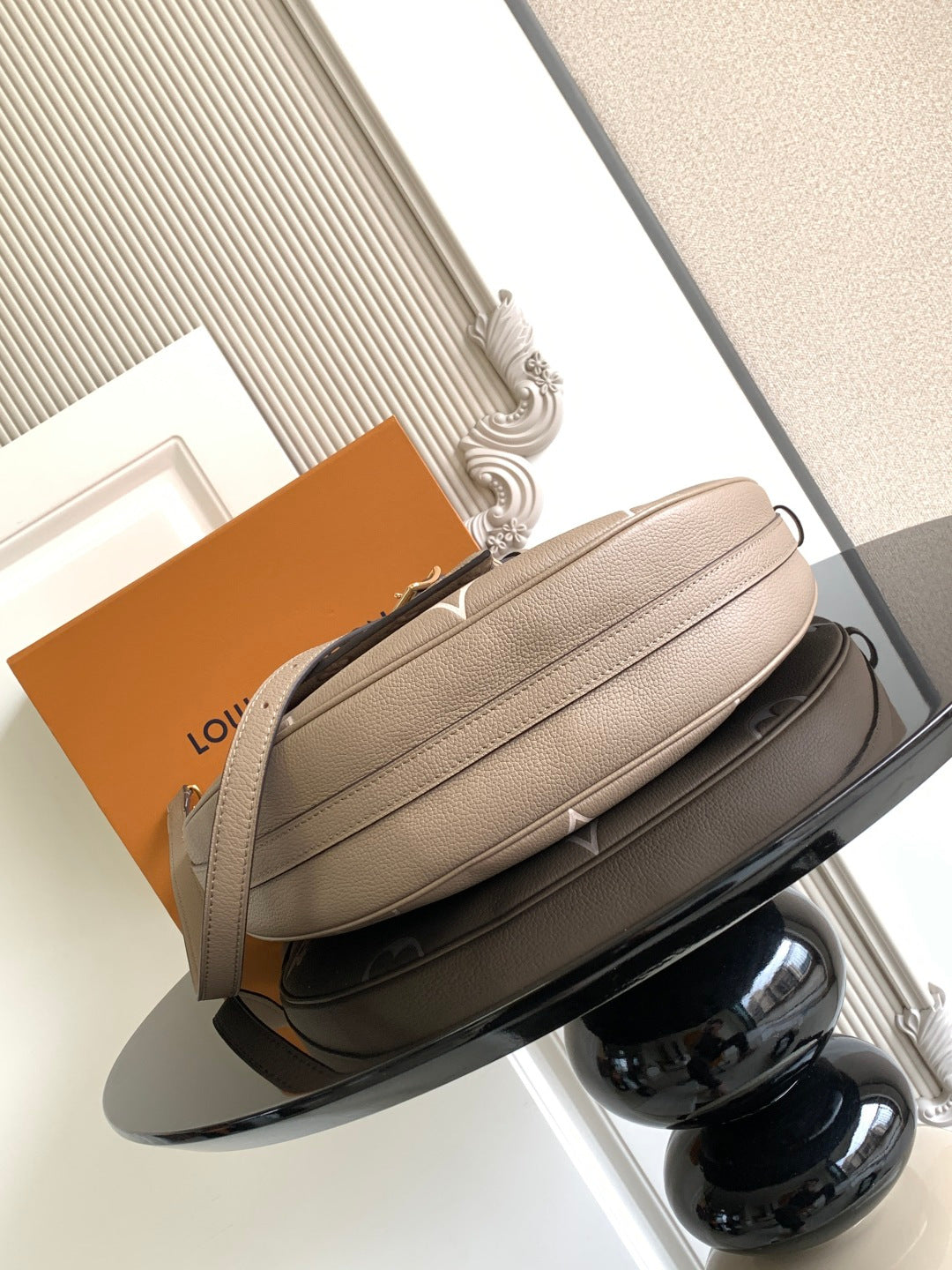 Taupe crossbody bag with structured shape, gold-toned chain strap, and top zip closure.