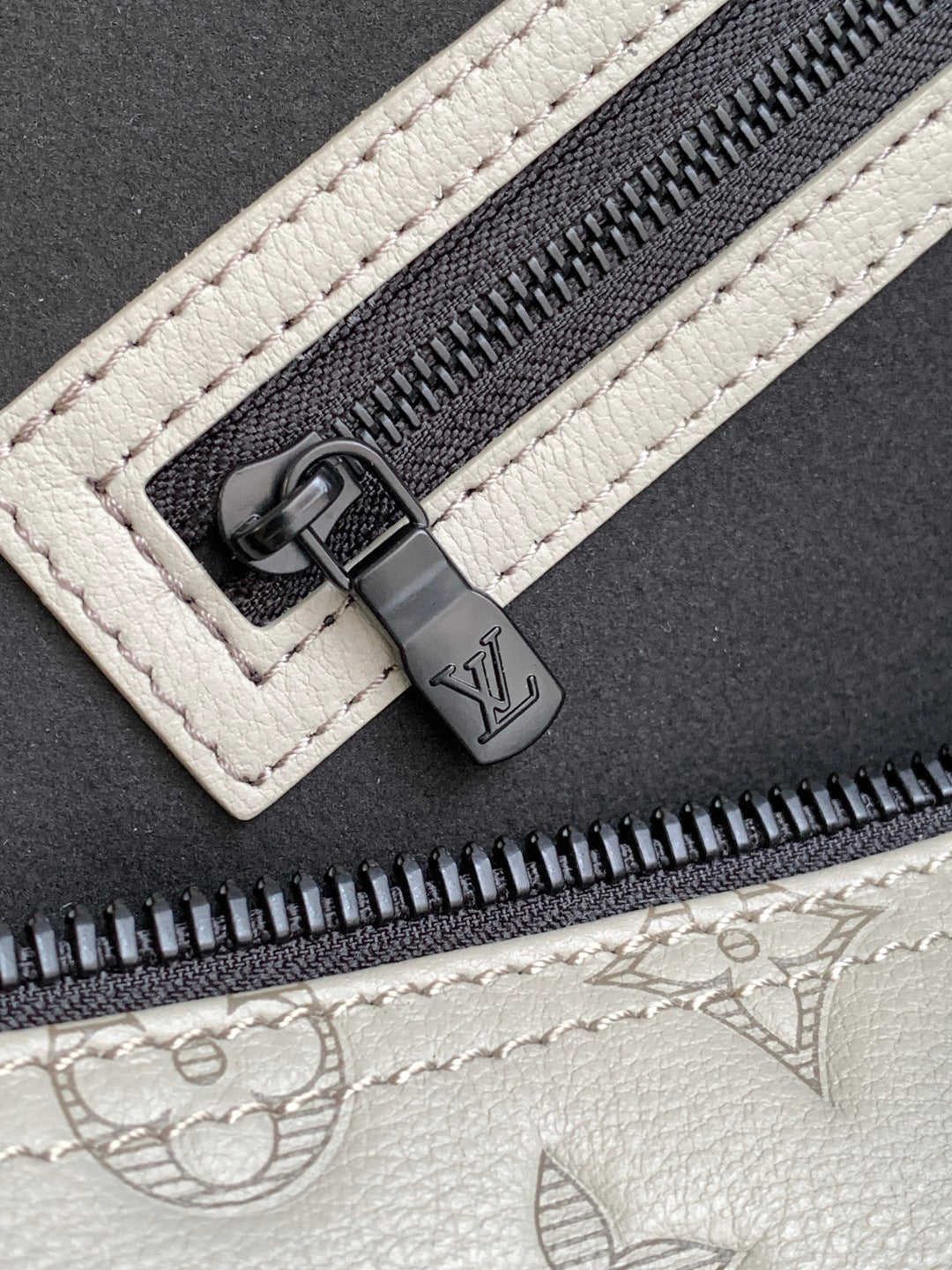 Monogram duffel bag zipper pull and track on light gray leather trim
