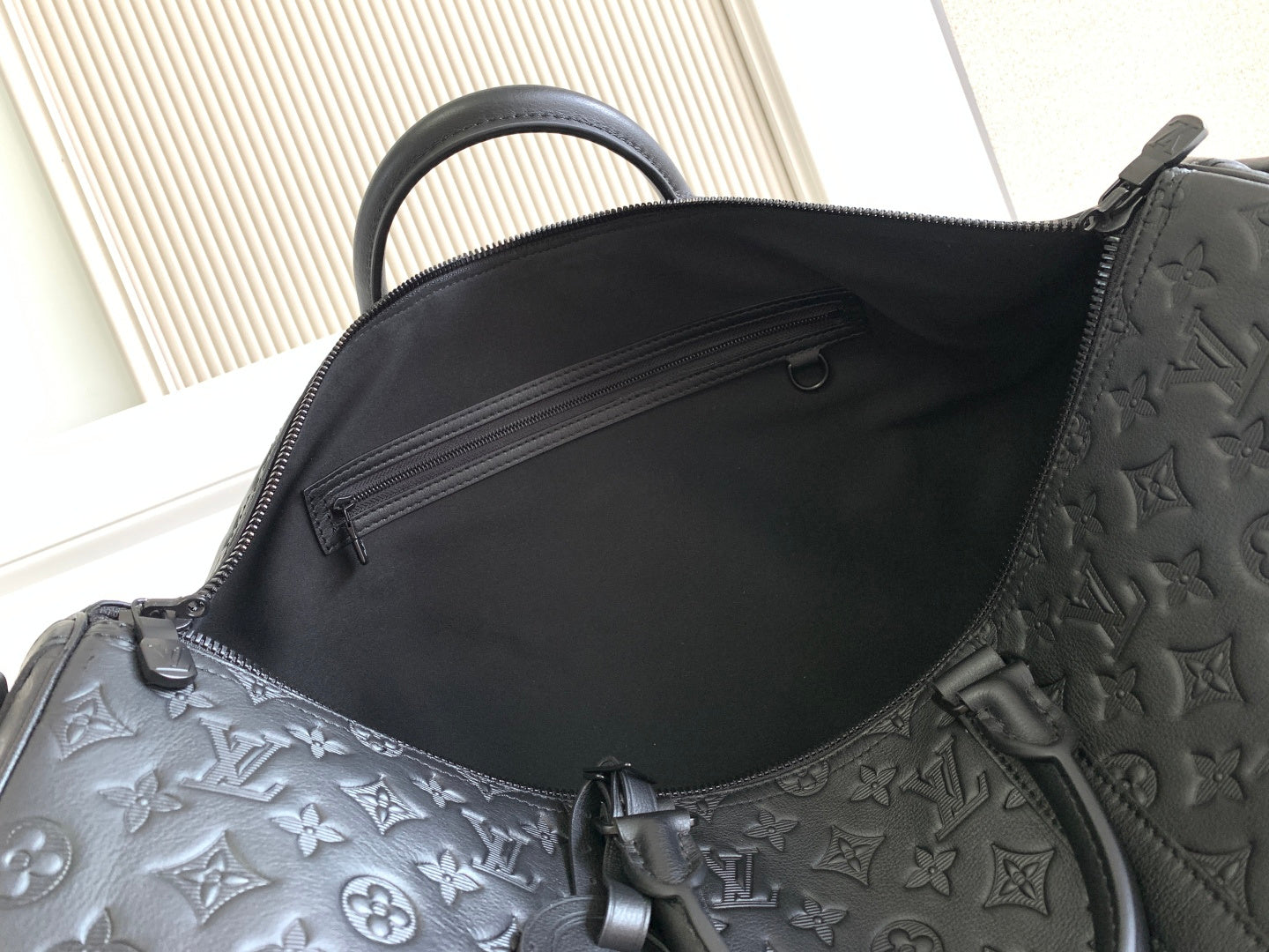 Louis Vuitton bag interior opening with dark fabric lining and embossed monogram edge