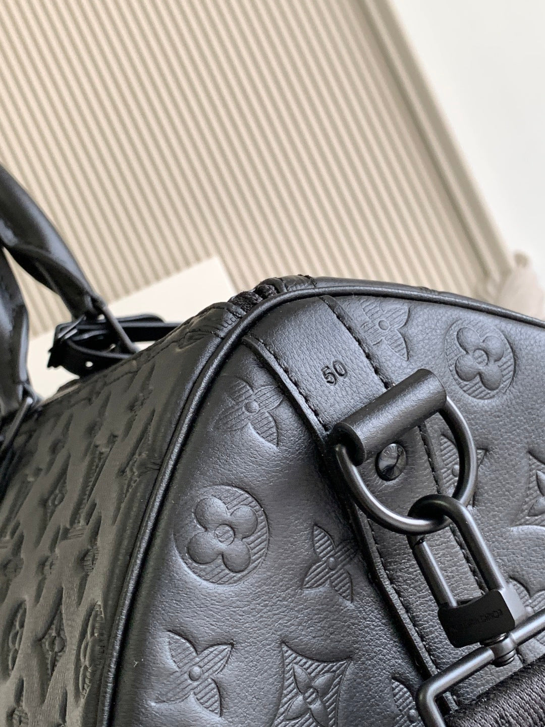 Louis Vuitton bag handle and D-ring detail on embossed monogram leather