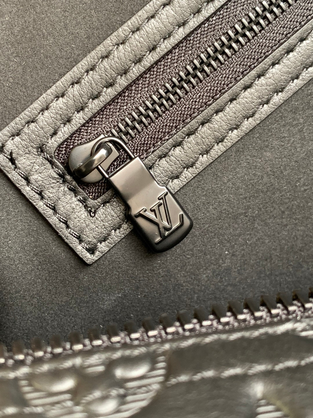 Louis Vuitton bag zipper pull and stitching detail with embossed leather and metal tab