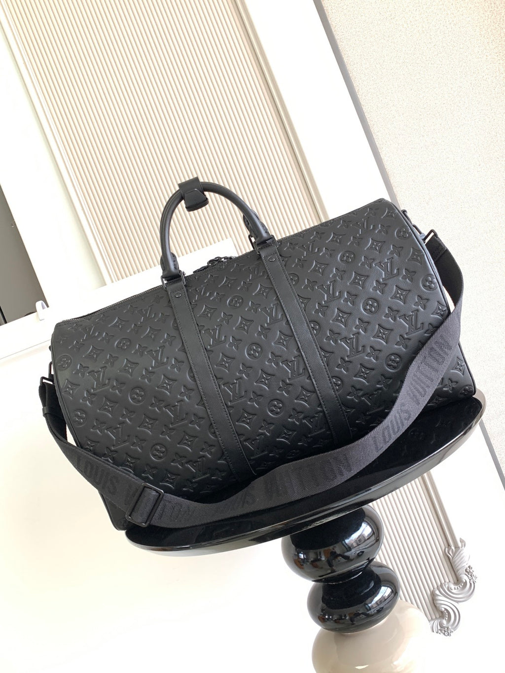 Louis Vuitton bag with embossed monogram texture, structured top and long shoulder strap
