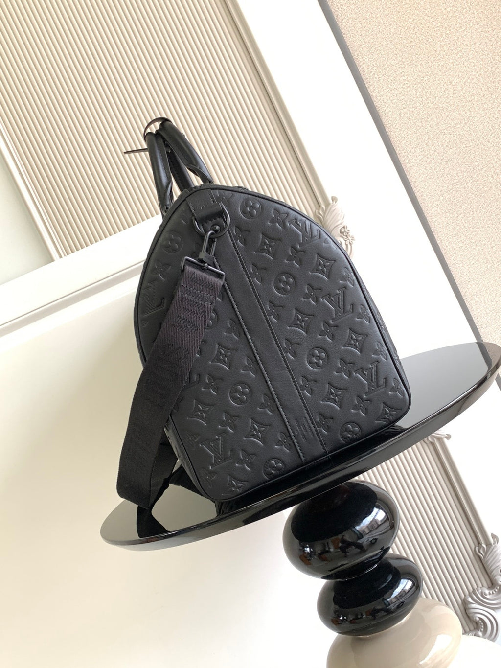 Louis Vuitton bag side view with embossed monogram design, shoulder strap and zipper