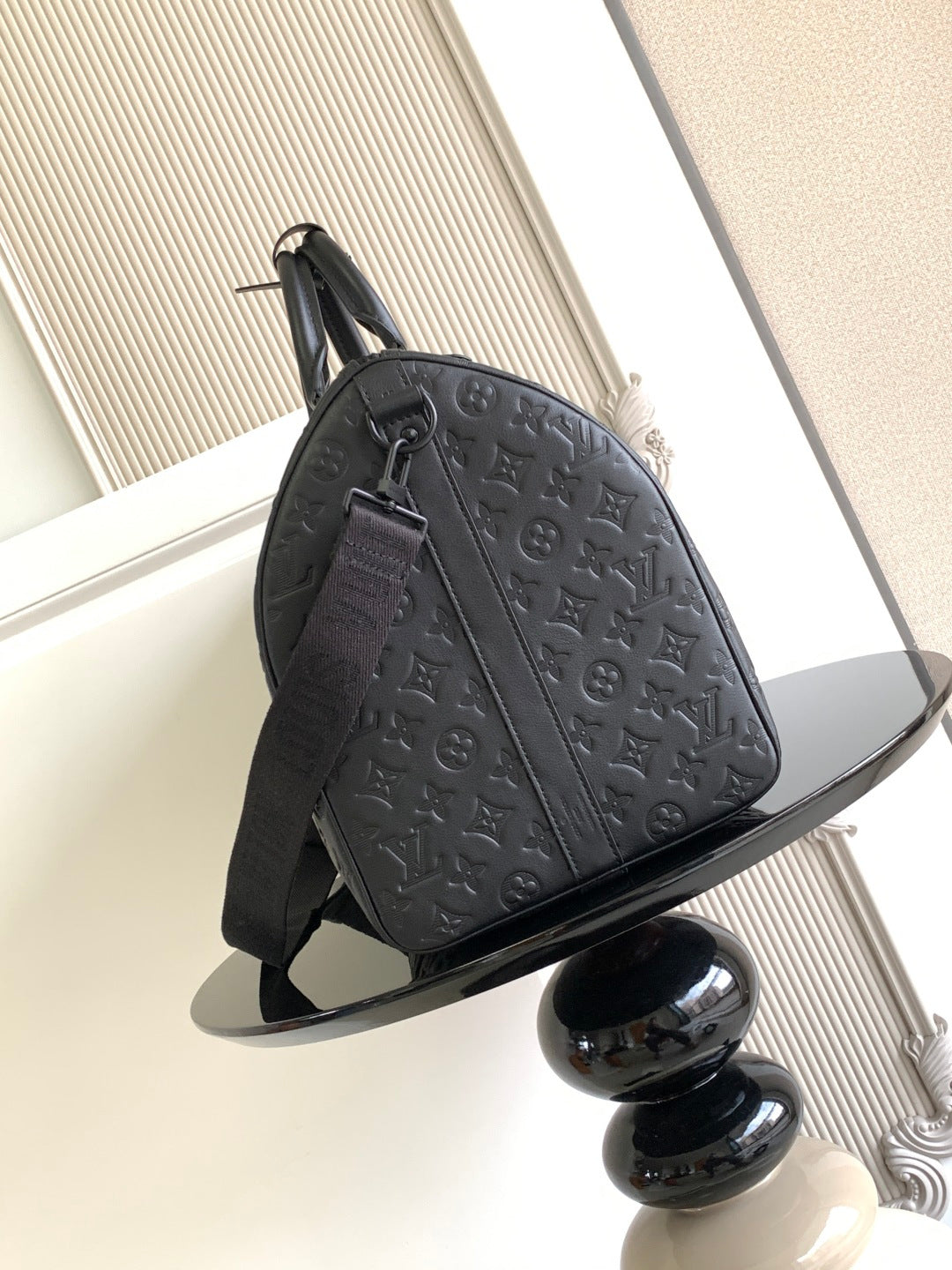Louis Vuitton bag side view with embossed monogram design, shoulder strap and zipper