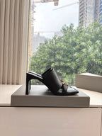 Black heeled slide sandal with open toe and gold-tone buckle on the strap