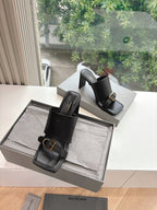 Pair of black heeled slide sandals with open sides and gold-tone buckle