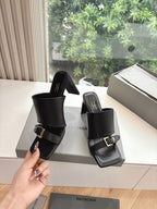 Black heeled slide sandals with thick band straps and gold-tone buckle hardware