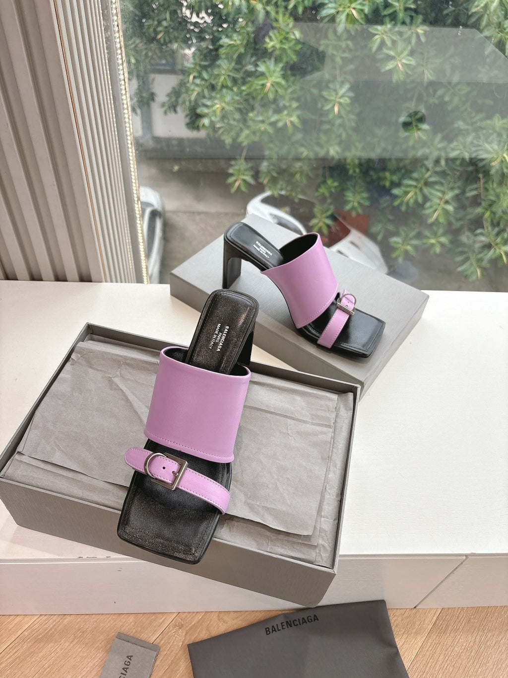Pair of pink slide sandals with black leather footbed and square buckle