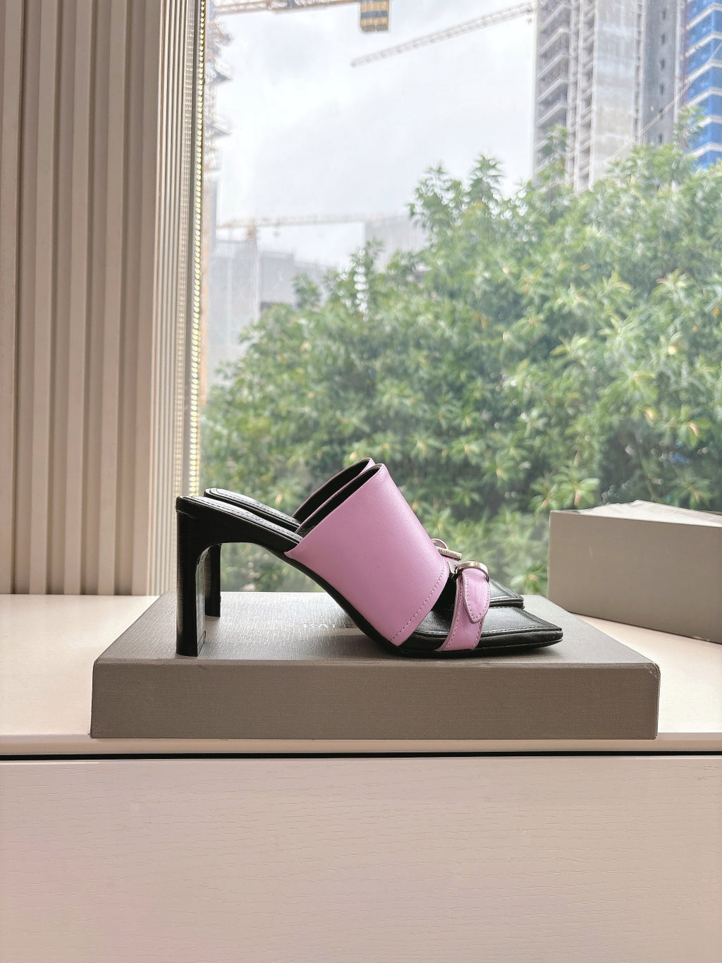 Black and pink slide sandal with open sides and block heel on display box