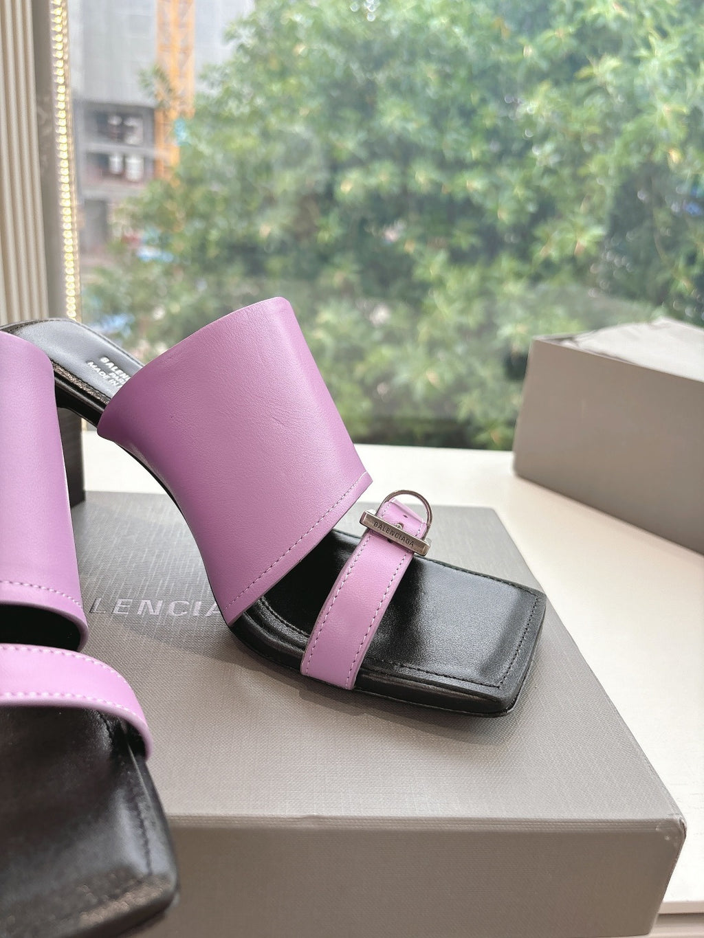 Close view of pink and black sandals with square buckle on strap