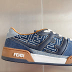 Close-up Fendi denim sneaker with FF emblem, tan side panel, white lace-up.