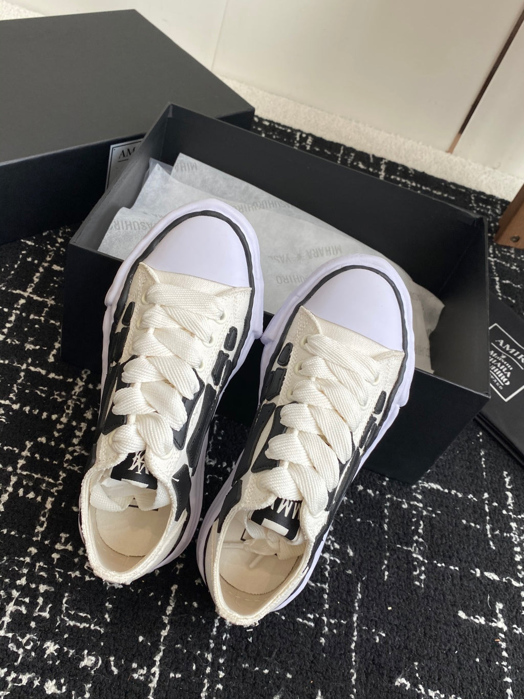 White lace-up sneakers with toe and laces visible, black trim on side