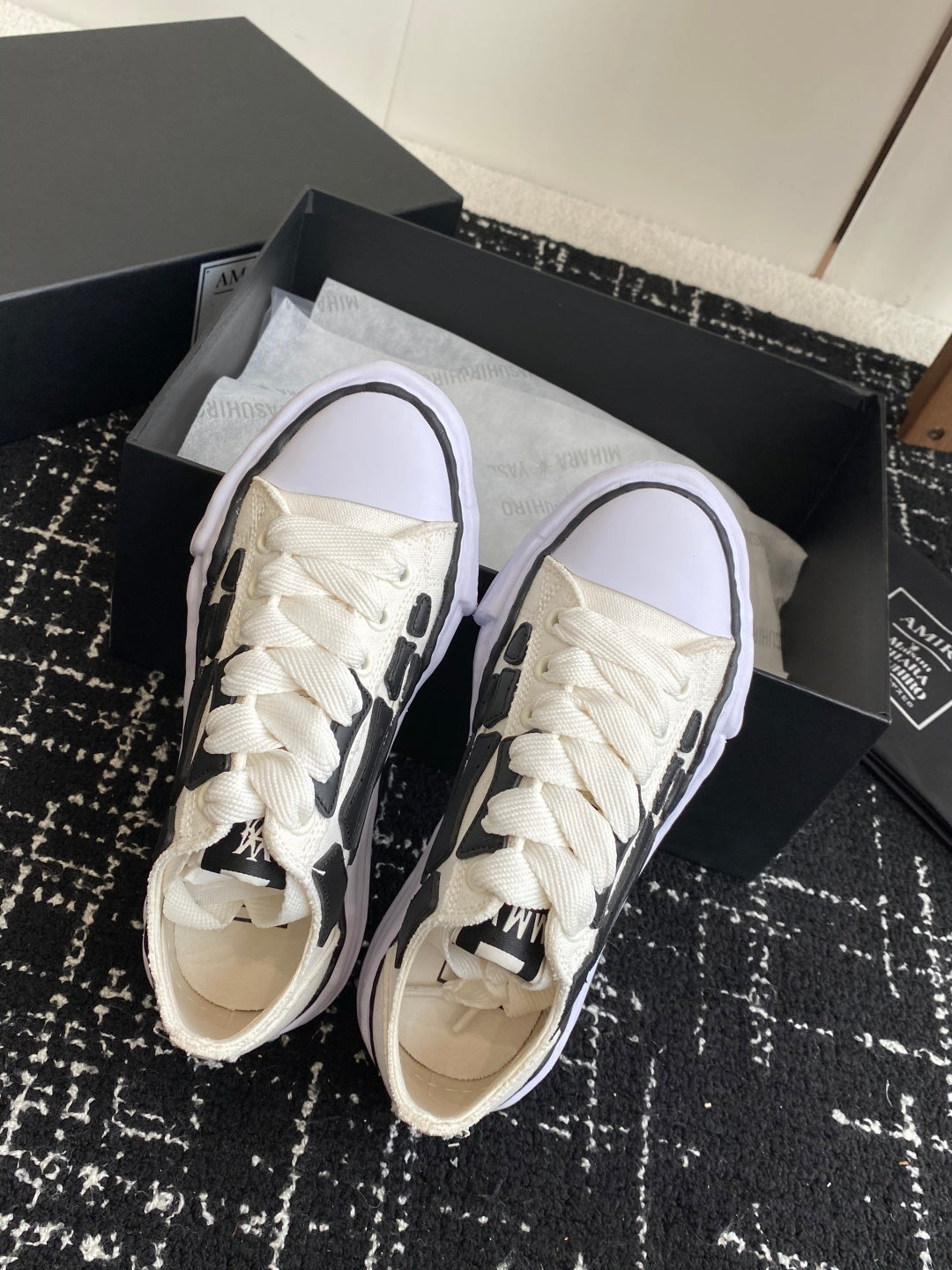 White lace-up sneakers with toe and laces visible, black trim on side