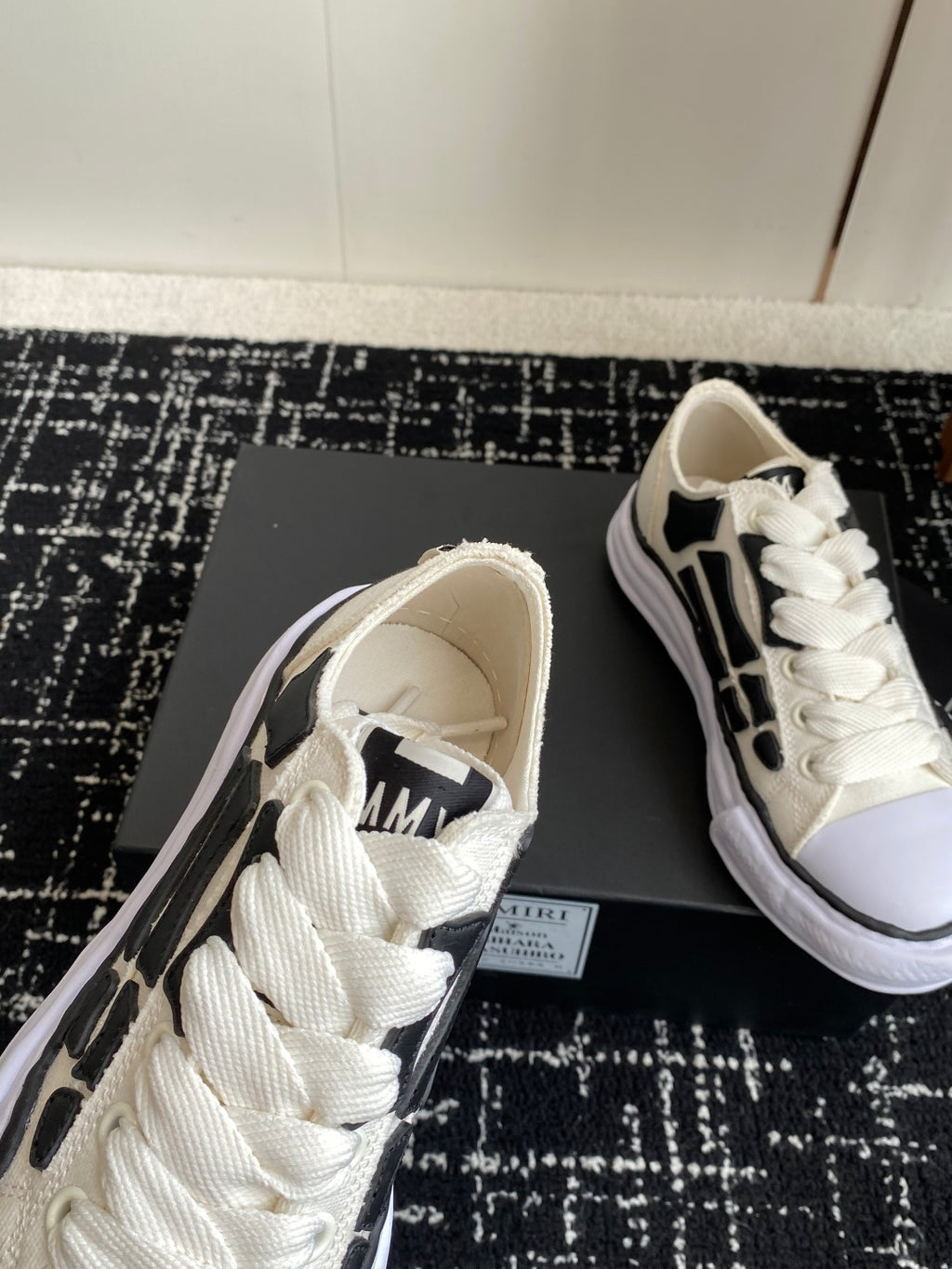 White lace-up sneaker showing tongue patch and black side logo detail