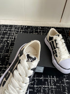 White lace-up sneaker showing tongue patch and black side logo detail