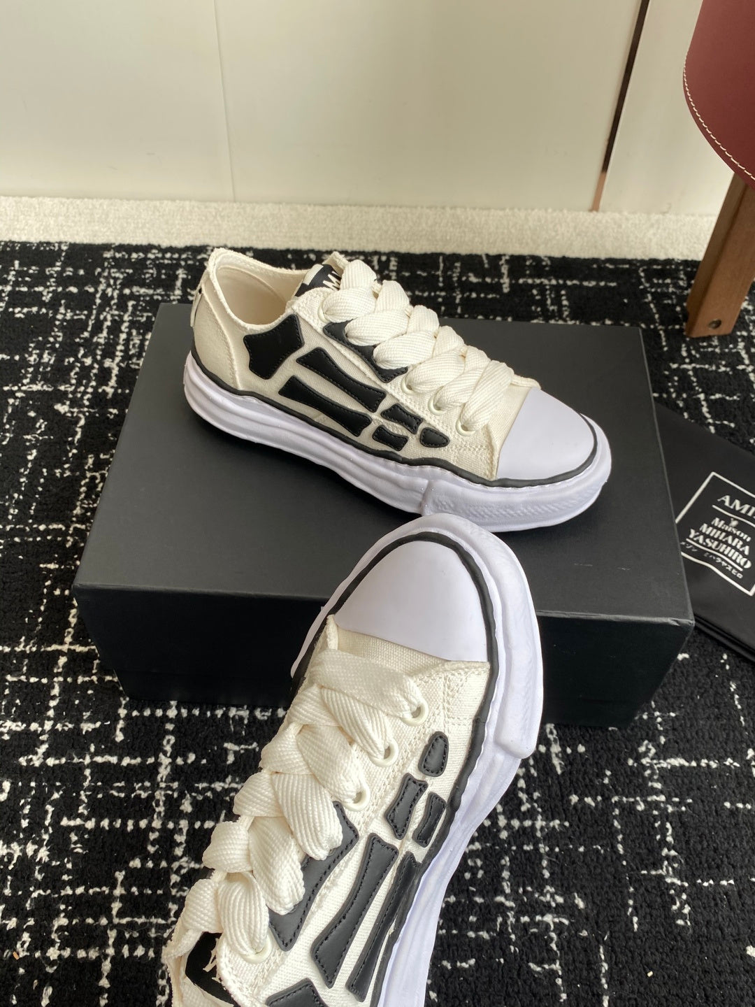 White lace-up sneakers with black logo side detail and thick white sole