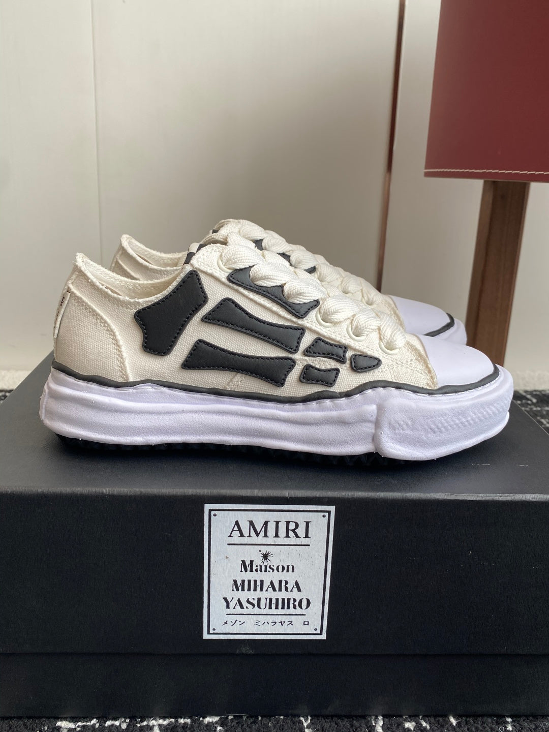 White lace-up sneakers with black graphic side stripe and thick white rubber sole