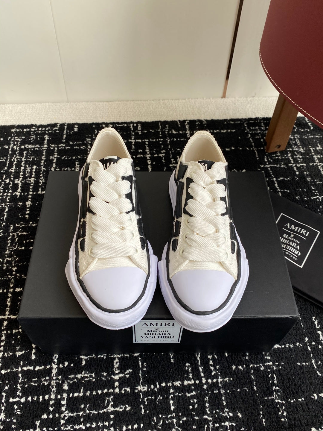 White lace-up low-top sneakers with black side pattern and cushioned white sole
