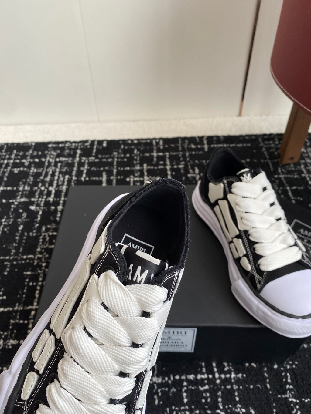 Black low-top sneakers with white laces and contrast side stripe, angled view