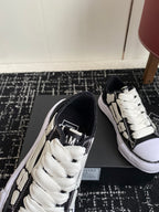 Black low-top sneakers with white laces and contrast side stripe, angled view