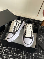Black and white low-top sneakers with white laces and patterned side trim