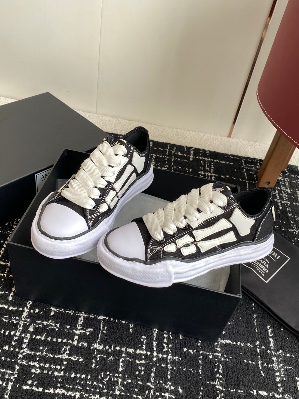 Pair of black and white low-top sneakers on box, white lace-up front