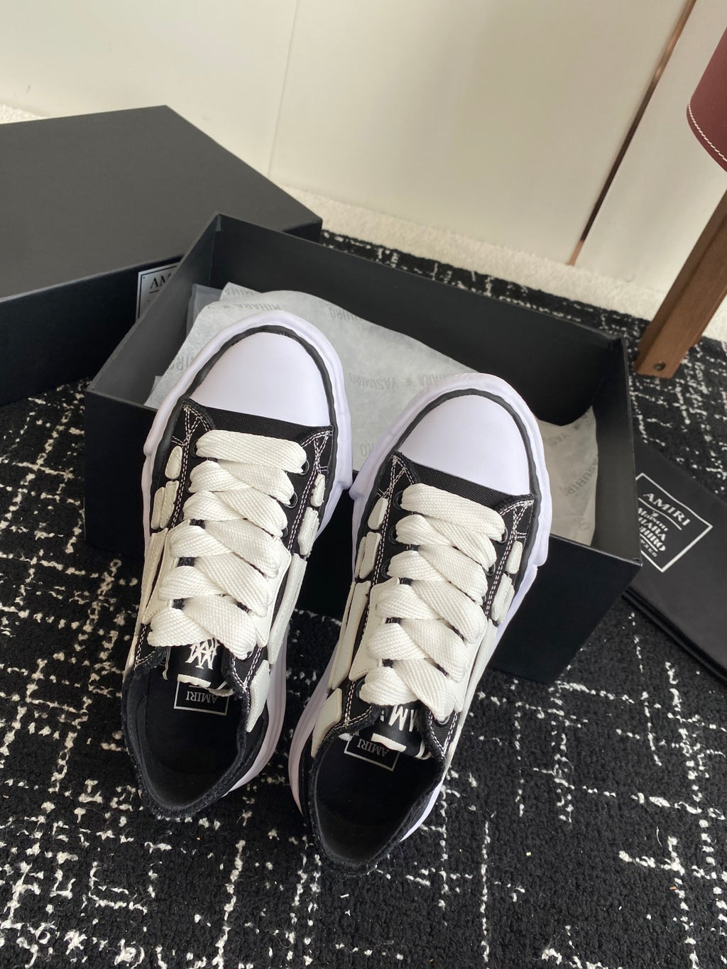 Black and white sneakers with white laces, rounded toe, lace-up detail