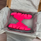 Bright pink Balenciaga slide sandals inside tissue paper packaging, front pair