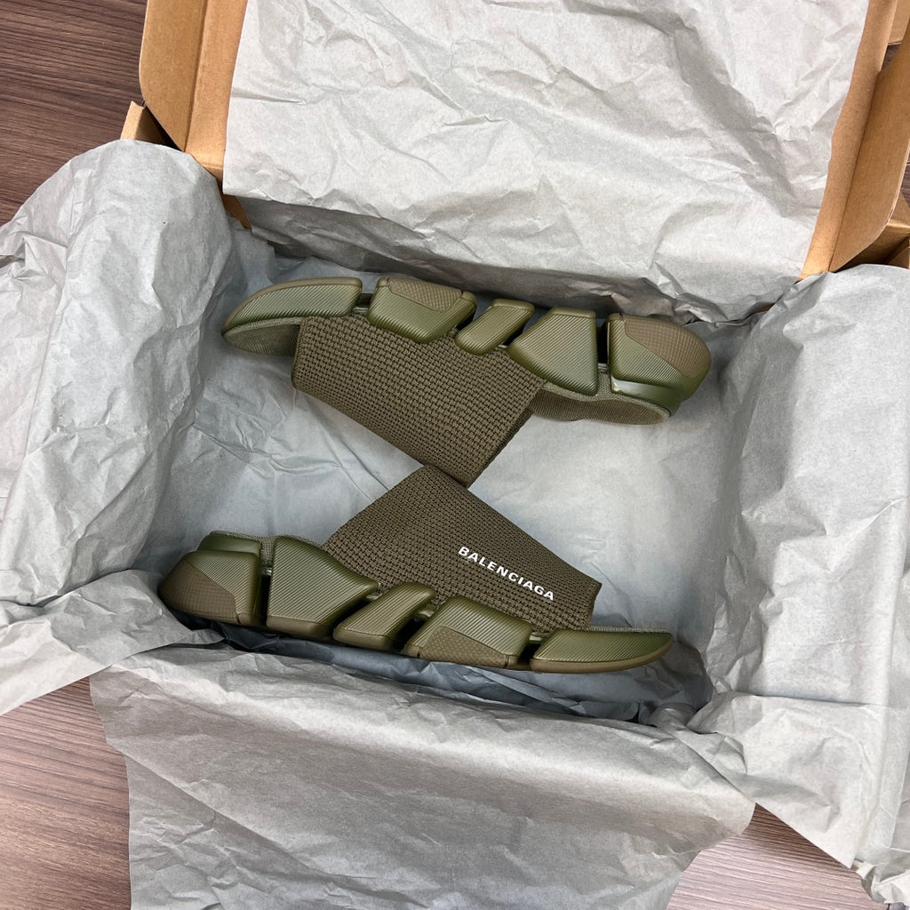 Green knit slide sandals inside crinkled packaging with chunky tread sole
