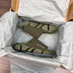Green knit slide sandals inside crinkled packaging with chunky tread sole