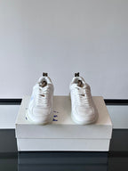 White low-top sneakers with laces and blue logo detail, rear quarter view