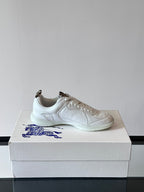 Pair of white low-top sneakers with blue logo embroidery on box, side view