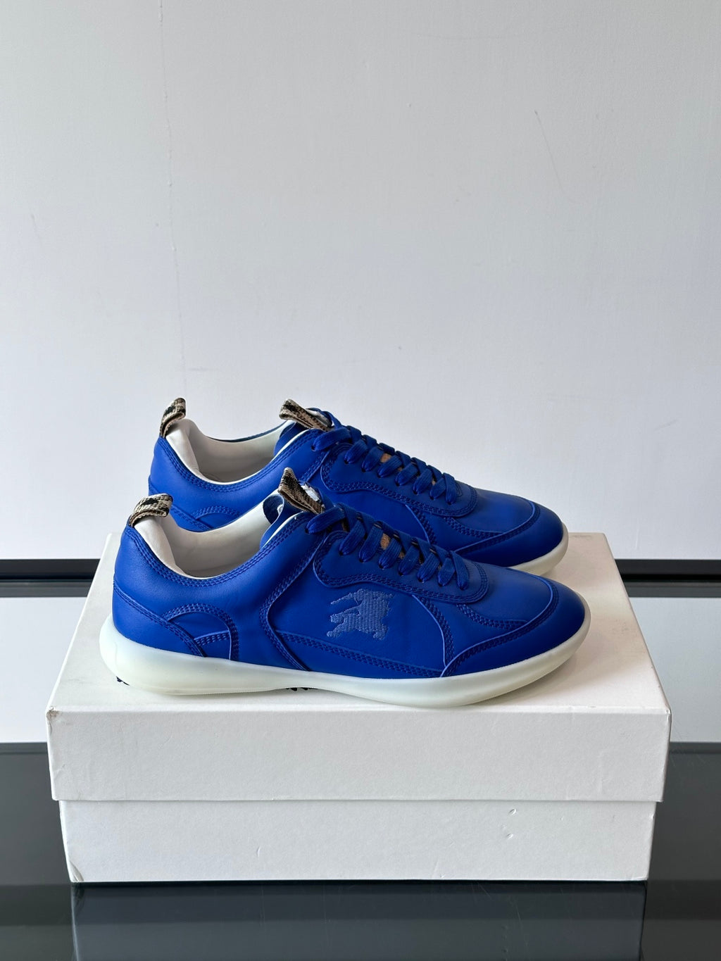 Blue lace-up sneakers with white rubber soles, shown as a pair on a box