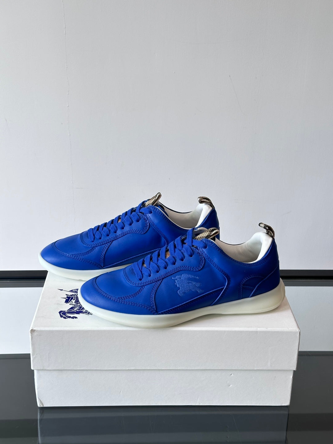 Blue lace-up sneakers with white soles, angled front view on a box