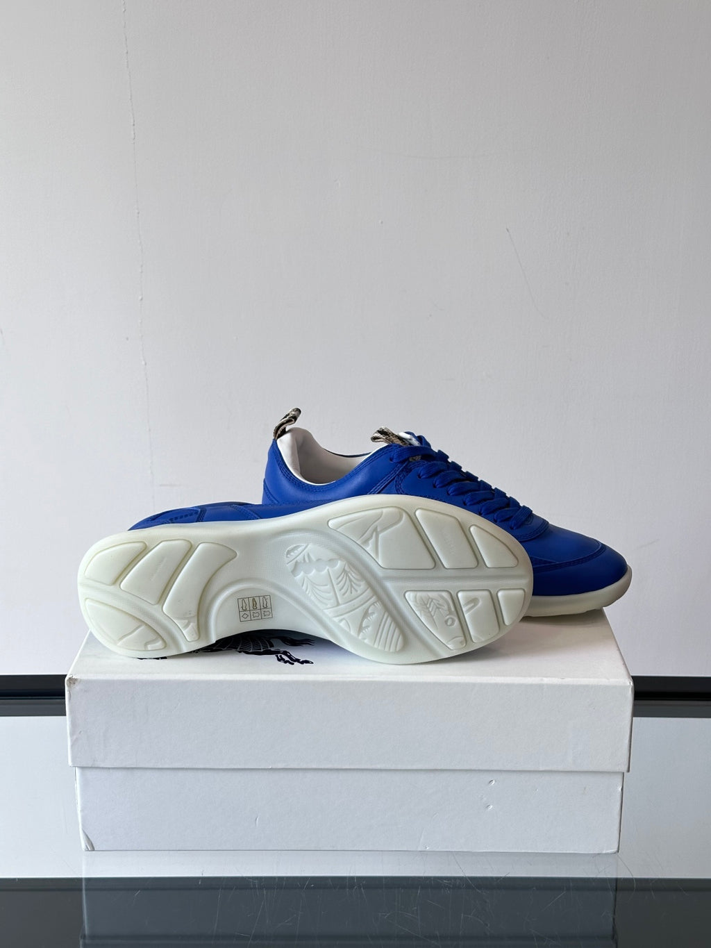 Blue lace-up sneaker outsole view, showing tread on white rubber sole