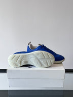 Blue lace-up sneaker outsole view, showing tread on white rubber sole