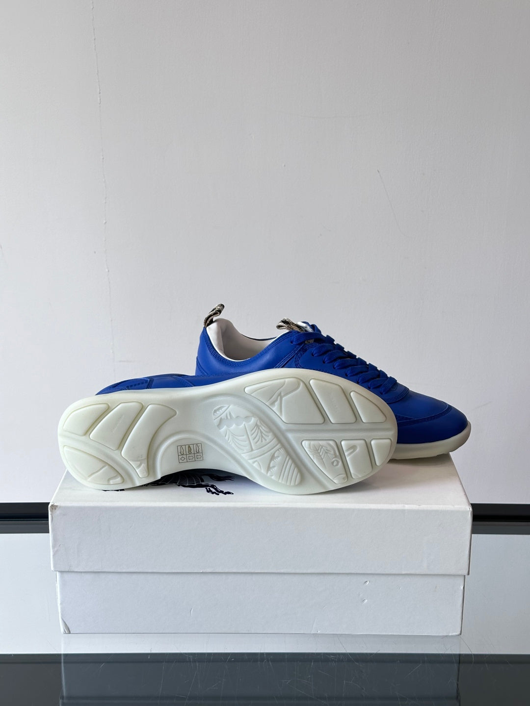 Blue lace-up sneaker outsole view, showing tread on white rubber sole